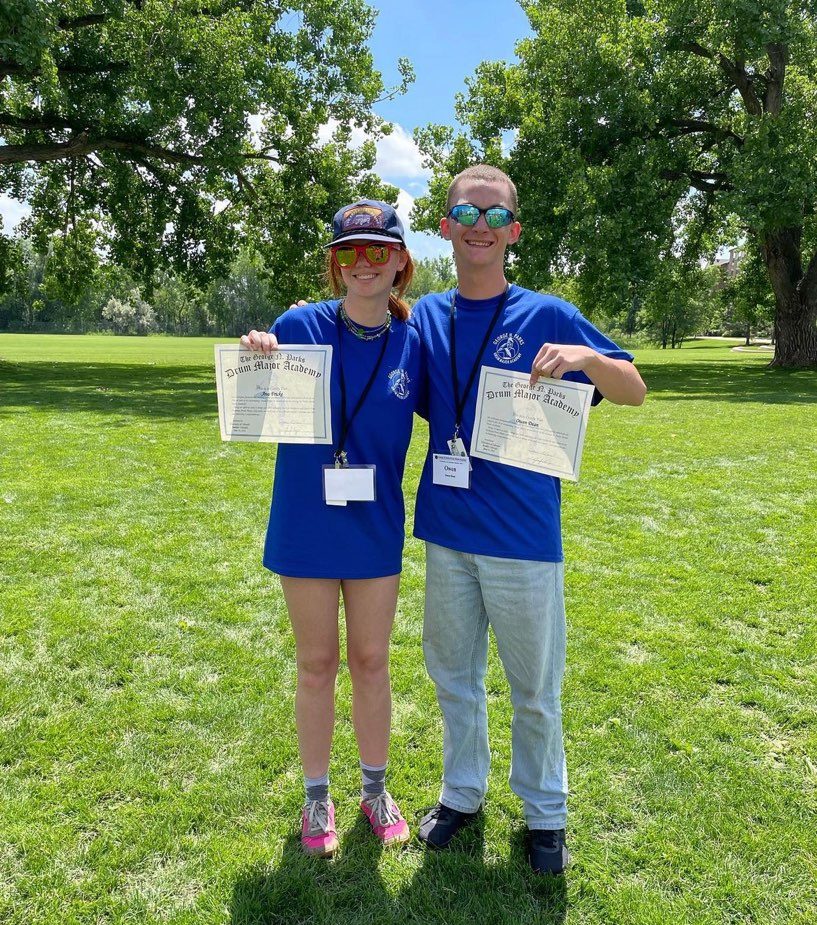 Ava and Owen holding their drum major academy certificates
