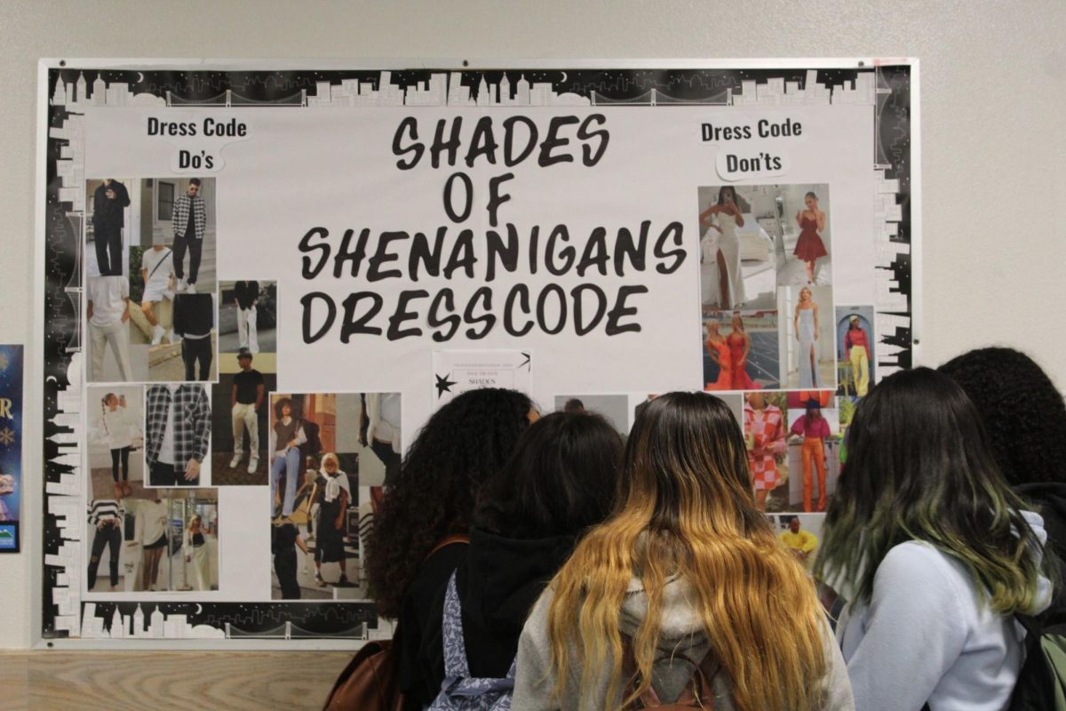 Students observing the Shades of Shenanigans Dress Code board by Dog Run.
