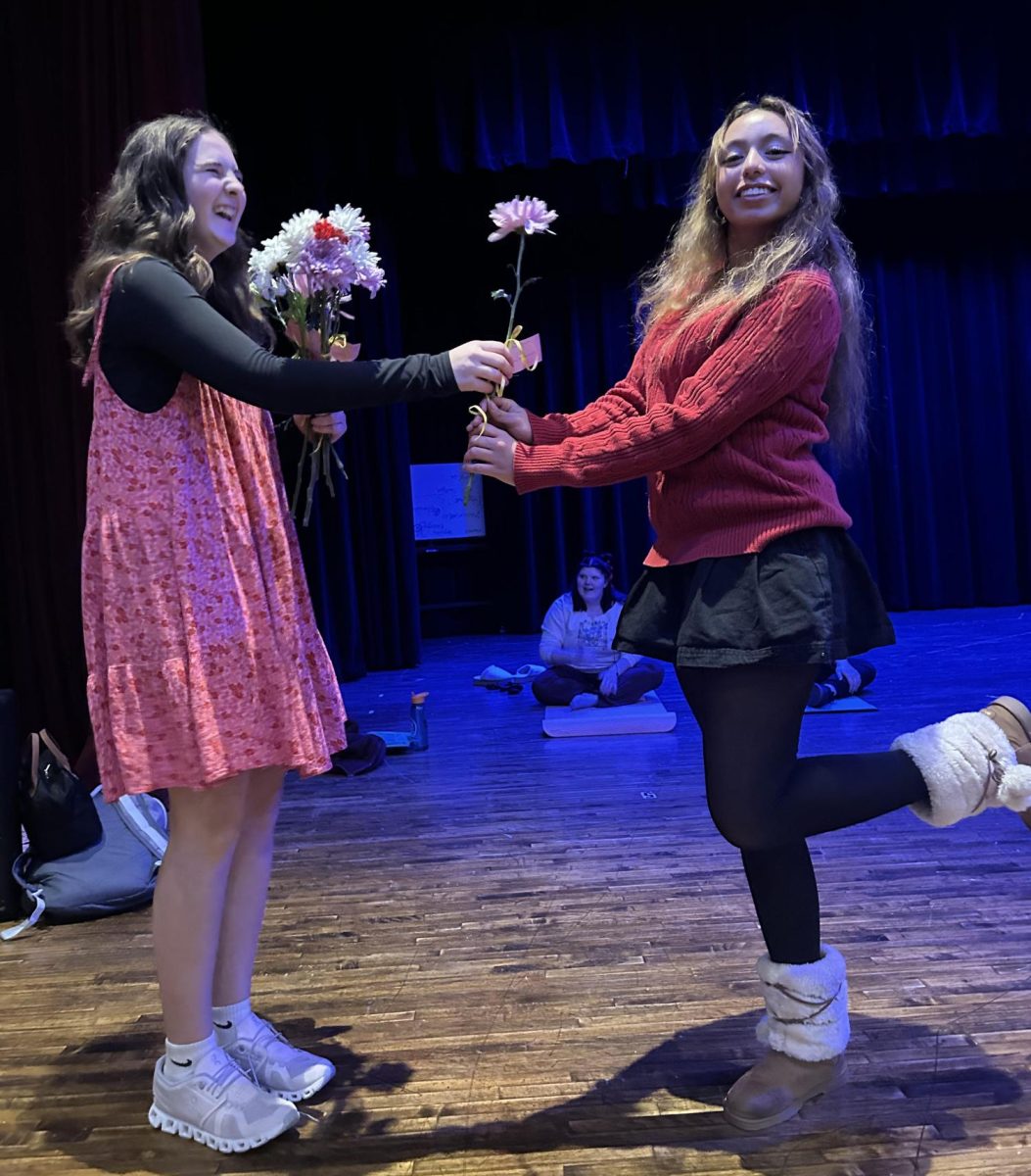 Genevive Seymour (left) handing Heidi Escobedo (right) a flower for Valentine’s Day. 