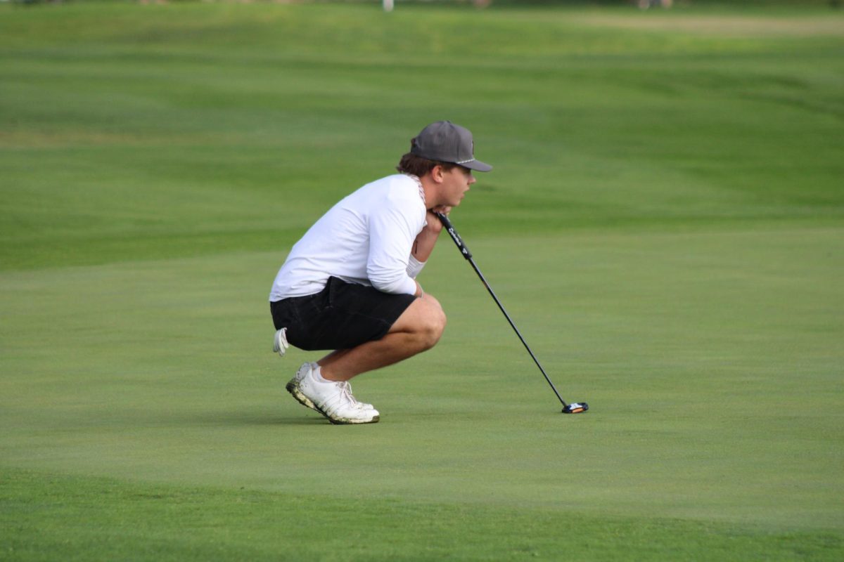 Senior Jackson Martin reading the green for his upcoming putt. 