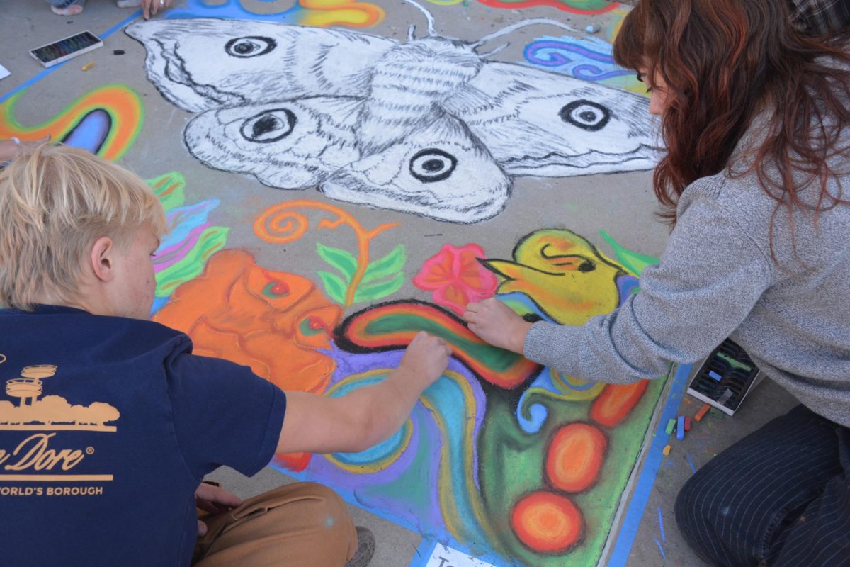 Seniors Hank DeFord and Annika Fitzgerald working on the background designs of their chalk art.