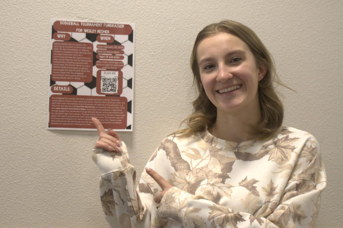 Reese Blackburn pointing at the poster she made to spread awareness for Wesley and the tournament.