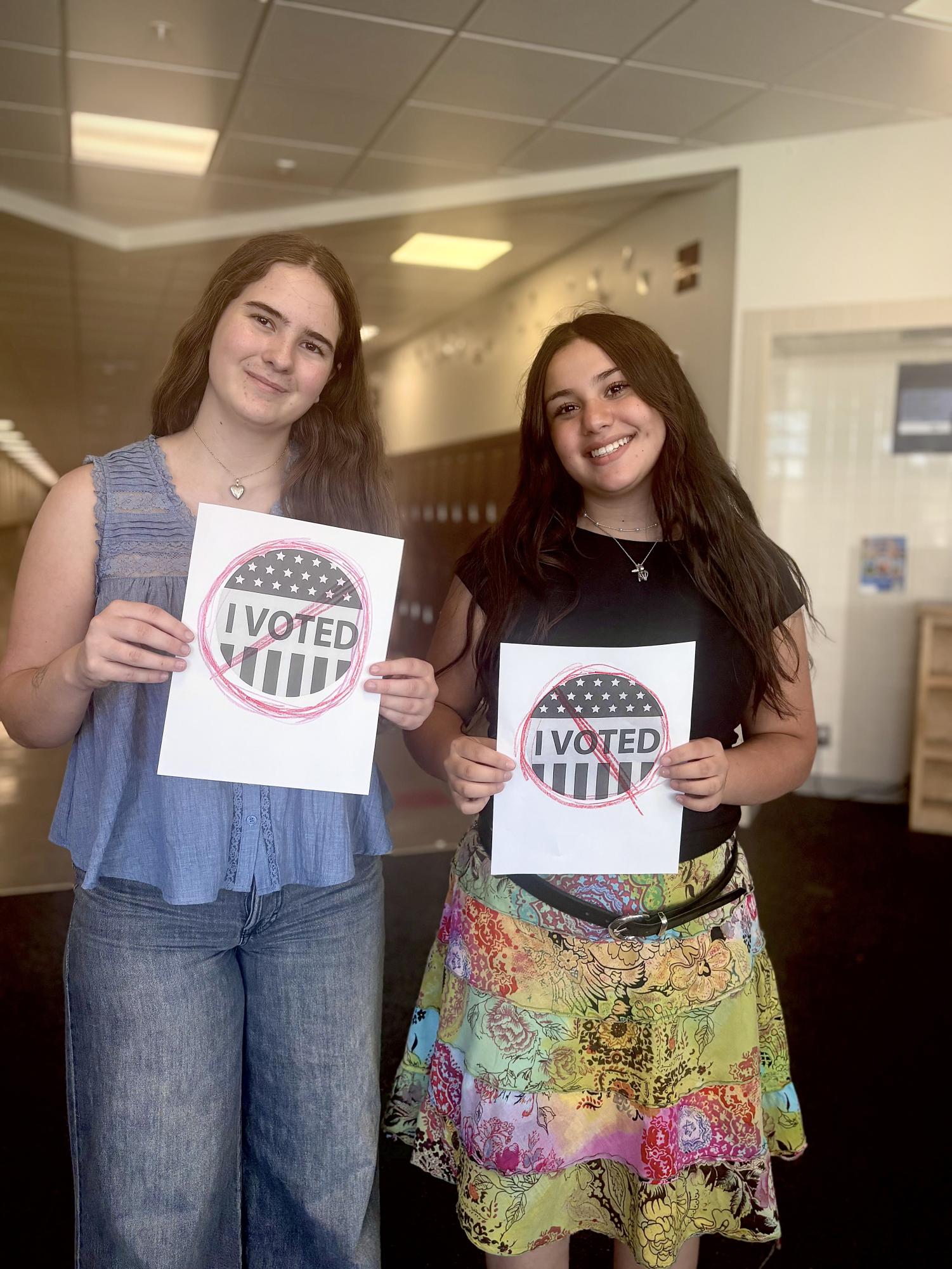 SBA Historian Genevieve Seymour and Cami Magallanes posing with signs saying that they didn’t vote for STUCO elections