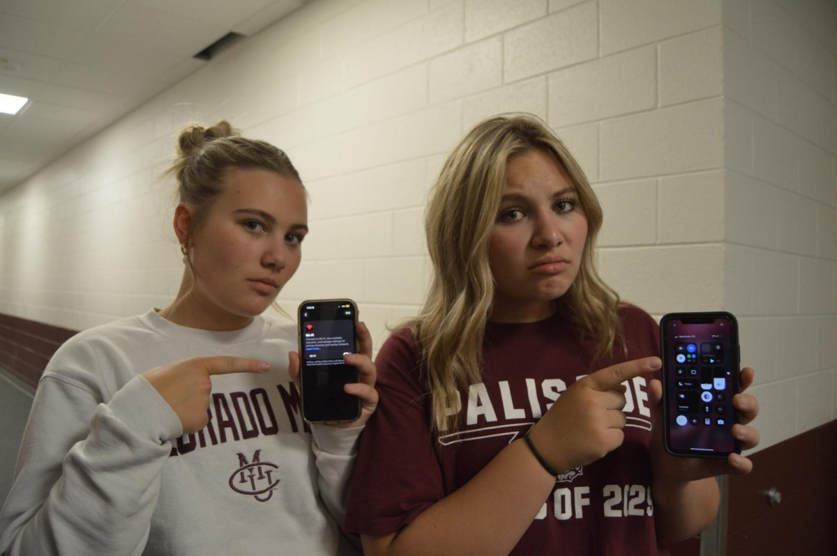 Twins Abi and Madi Ellison posing with their phones, as they have no wifi.
